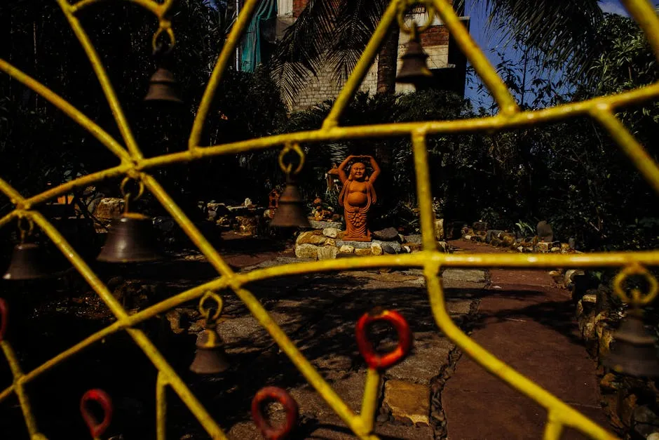 Yellow fence from iron in front of yard with Buddha statue and stones