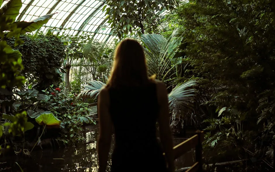 A woman is watching the greenhouse scenery from behind