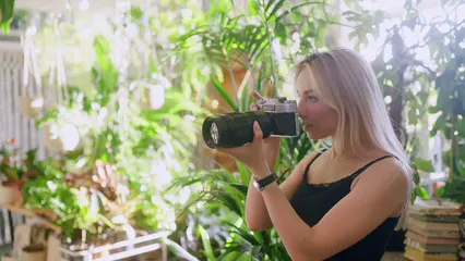 Horizontal video: A pretty woman taking photos in a room full of plants 8514986. Duration: 25 seconds. Resolution: 3840x2160