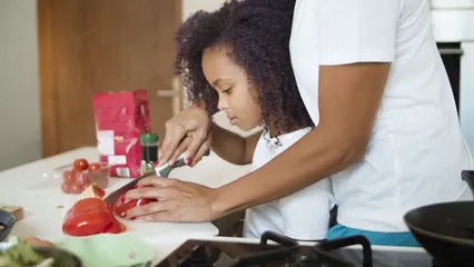 Horizontal video: A person teaching a young girl how to slice a tomato 6297036. Duration: 9 seconds. Resolution: 3840x2160