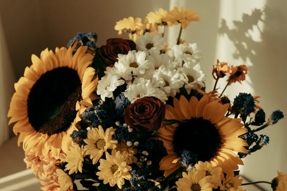 A stunning arrangement of sunflowers, roses, and daisies beautifully lit by warm sunlight.