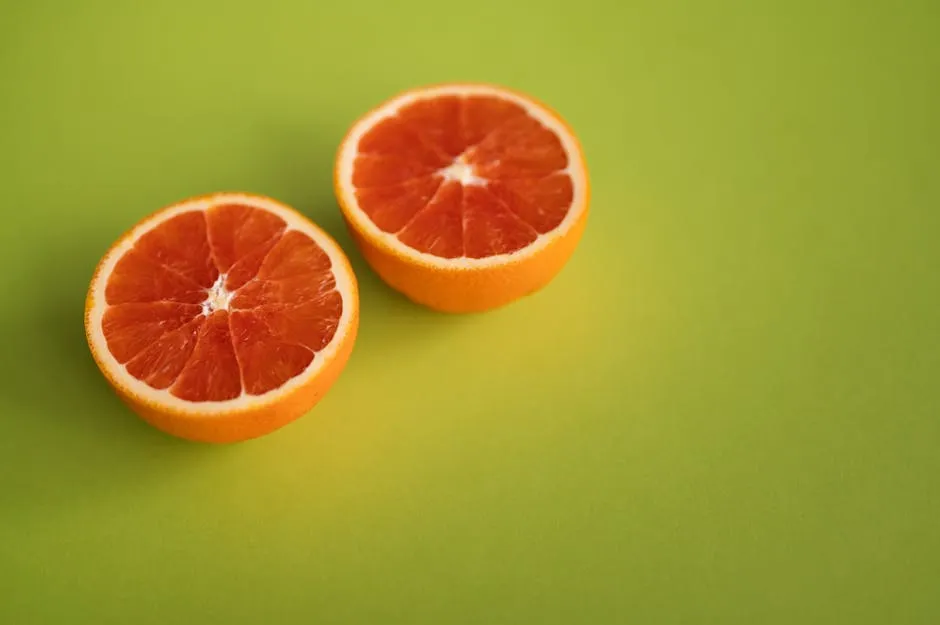 Tasty ripe citrus fruit with juicy pulp cut in half placed together on bright green surface